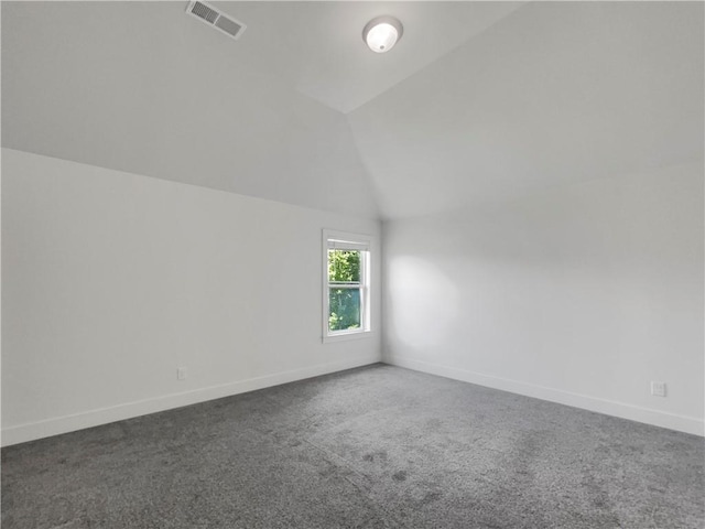 spare room featuring carpet flooring and vaulted ceiling