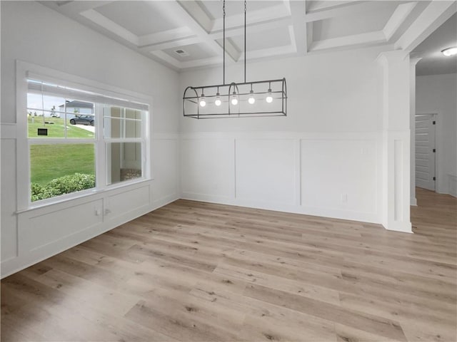 unfurnished dining area with coffered ceiling, a wainscoted wall, beamed ceiling, light wood-type flooring, and a decorative wall