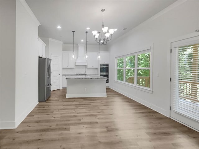 kitchen featuring appliances with stainless steel finishes, a kitchen island with sink, hanging light fixtures, and white cabinetry