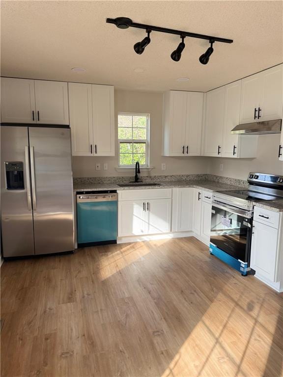 kitchen featuring sink, stainless steel appliances, white cabinetry, and light wood-type flooring