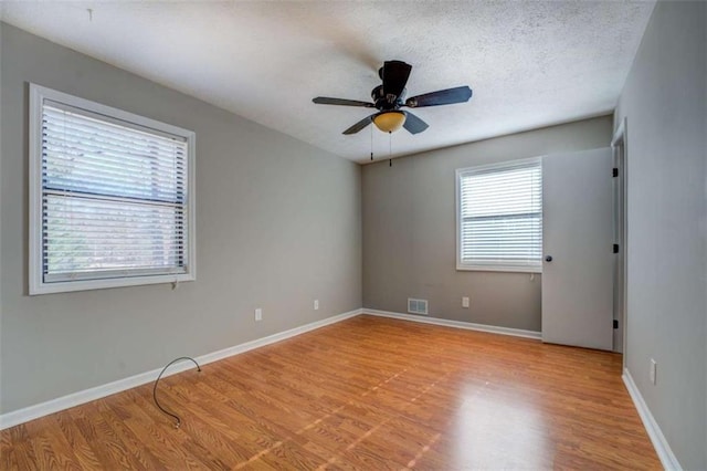 spare room featuring ceiling fan, light hardwood / wood-style floors, and a textured ceiling