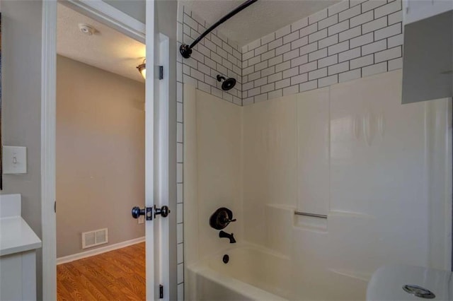 bathroom with hardwood / wood-style flooring and tiled shower / bath combo