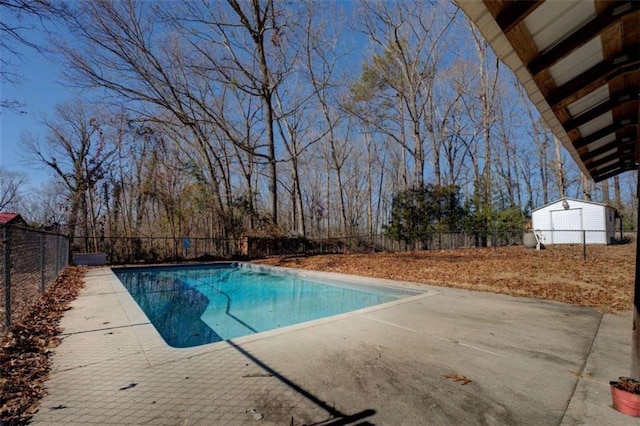 view of pool with a shed and a patio area