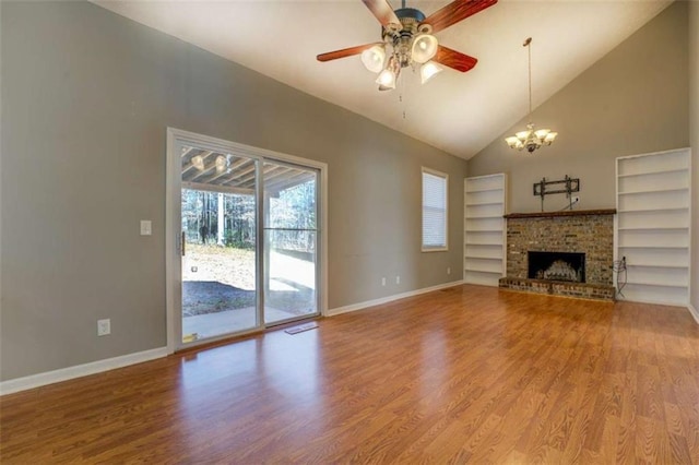 unfurnished living room with hardwood / wood-style flooring, built in shelves, ceiling fan with notable chandelier, and a brick fireplace