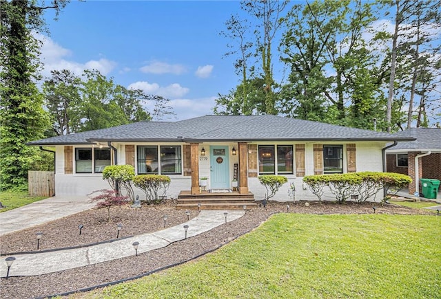single story home featuring brick siding, roof with shingles, and a front lawn