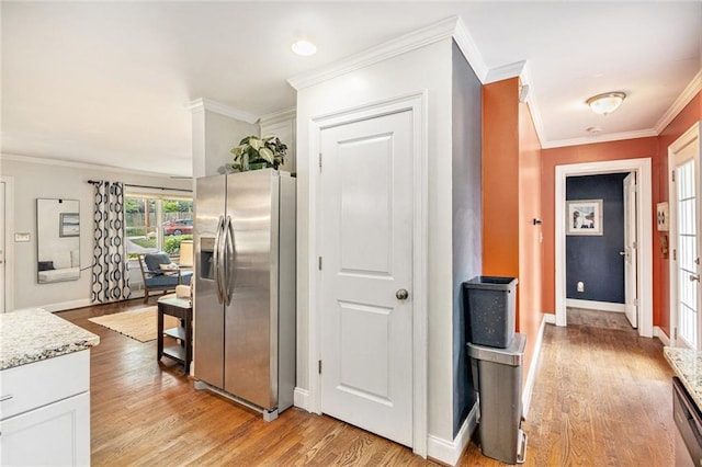 hallway with crown molding, baseboards, and light wood-style floors