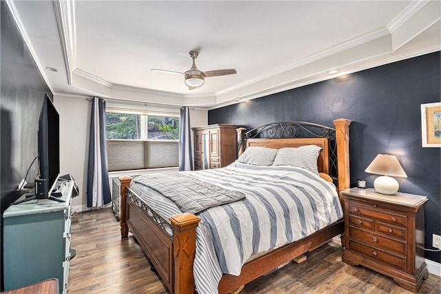 bedroom with a ceiling fan, a tray ceiling, ornamental molding, and wood finished floors
