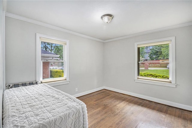 bedroom with baseboards, multiple windows, and wood finished floors