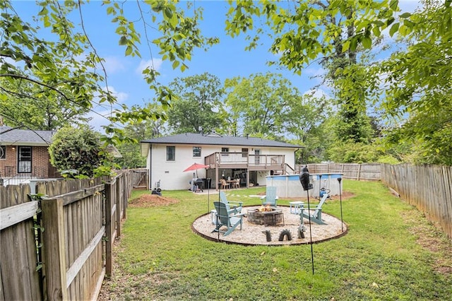 back of property featuring a fenced backyard, a fenced in pool, a wooden deck, and a fire pit
