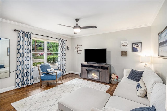 living area with baseboards, ceiling fan, ornamental molding, and wood finished floors