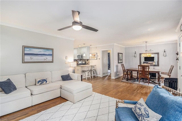 living room featuring baseboards, ceiling fan, ornamental molding, and wood finished floors