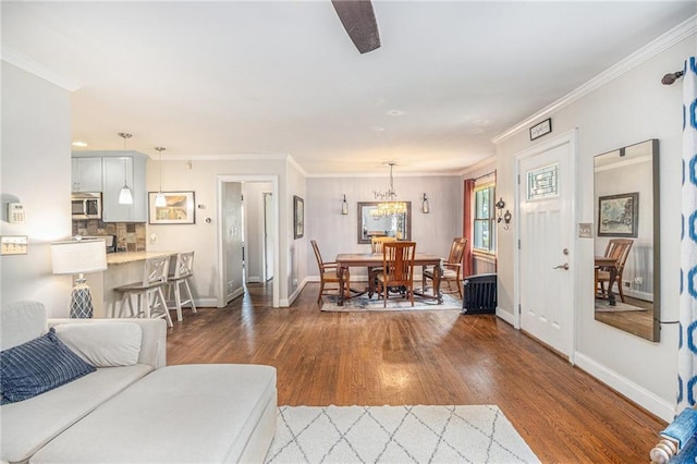 living room featuring baseboards, ornamental molding, and wood finished floors