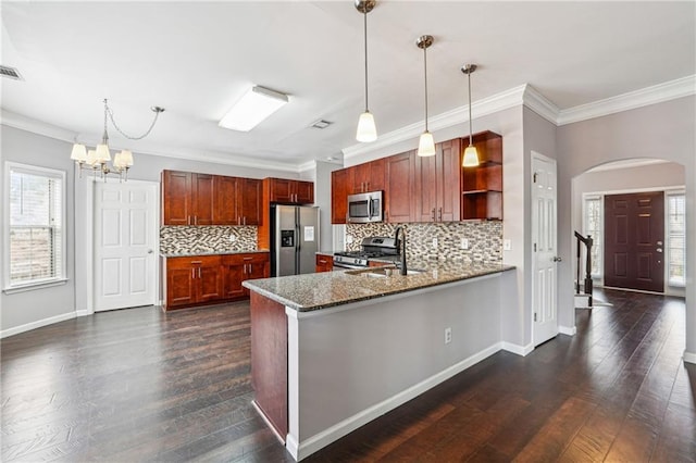 kitchen featuring a peninsula, arched walkways, a sink, dark wood-type flooring, and appliances with stainless steel finishes