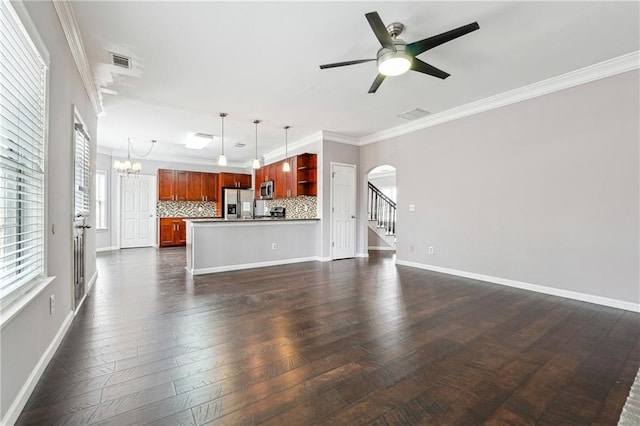 unfurnished living room with visible vents, baseboards, arched walkways, crown molding, and ceiling fan with notable chandelier