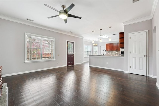 unfurnished living room with ceiling fan with notable chandelier, baseboards, and ornamental molding