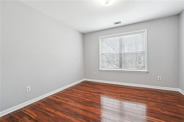 empty room with visible vents, baseboards, and dark wood-style flooring