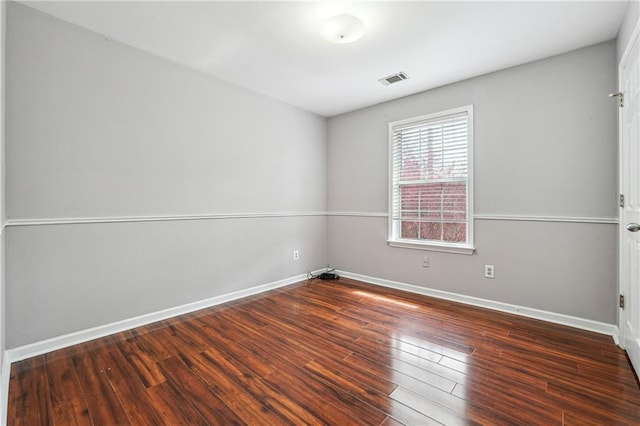 spare room featuring visible vents, baseboards, and wood finished floors