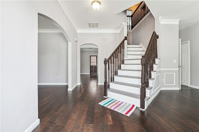 entryway featuring arched walkways, visible vents, baseboards, and wood finished floors