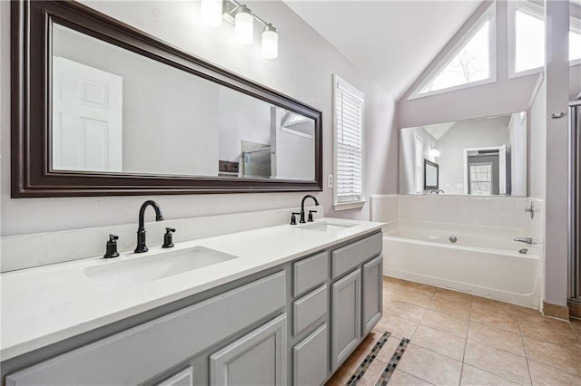 full bathroom with vaulted ceiling, plenty of natural light, tile patterned floors, and a sink