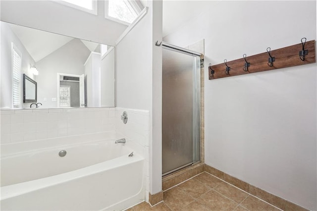 full bathroom with tile patterned flooring, a shower stall, a garden tub, and vaulted ceiling