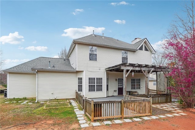 back of property with a shingled roof, a deck, and a pergola