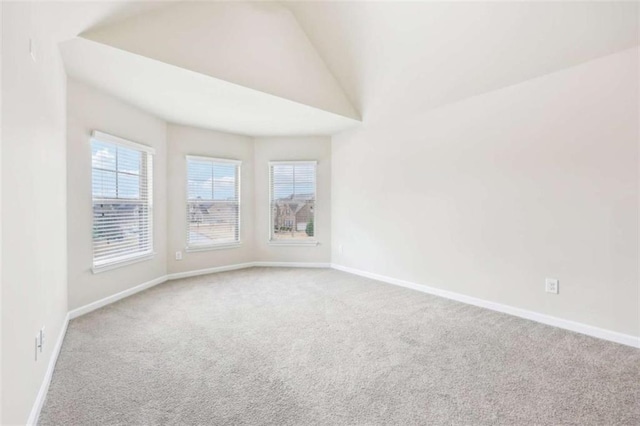 carpeted spare room with vaulted ceiling