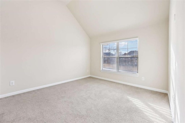 carpeted empty room featuring lofted ceiling