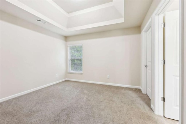 carpeted spare room featuring a tray ceiling