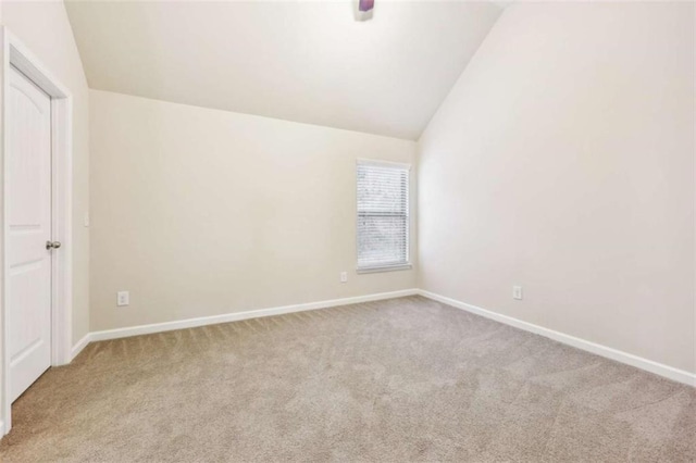 carpeted empty room featuring vaulted ceiling