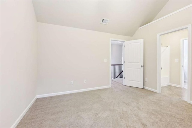 unfurnished bedroom featuring light colored carpet and vaulted ceiling