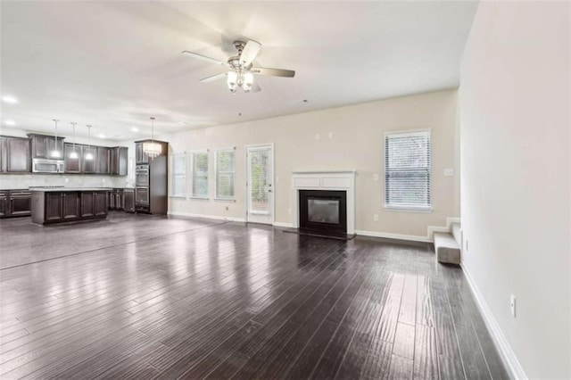 unfurnished living room featuring ceiling fan and dark wood-type flooring