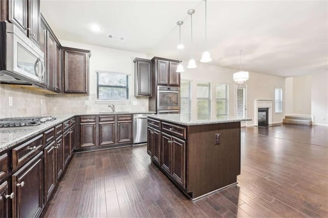 kitchen with dark brown cabinets, a kitchen island, hanging light fixtures, and appliances with stainless steel finishes