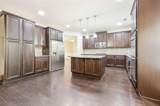 kitchen with dark brown cabinetry, a center island, backsplash, decorative light fixtures, and appliances with stainless steel finishes