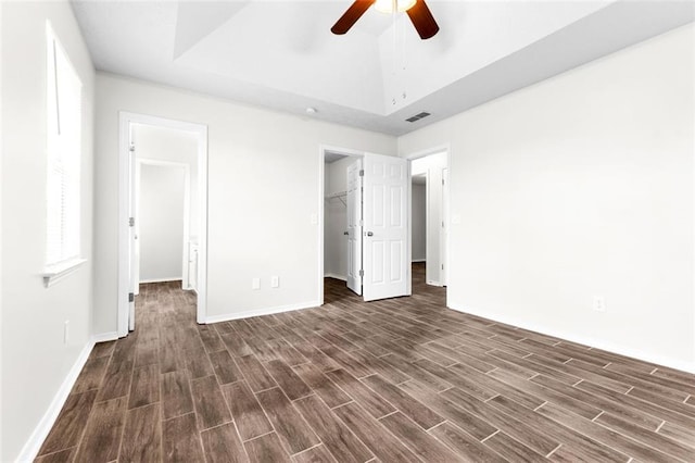 unfurnished bedroom with lofted ceiling, a walk in closet, a closet, and ceiling fan