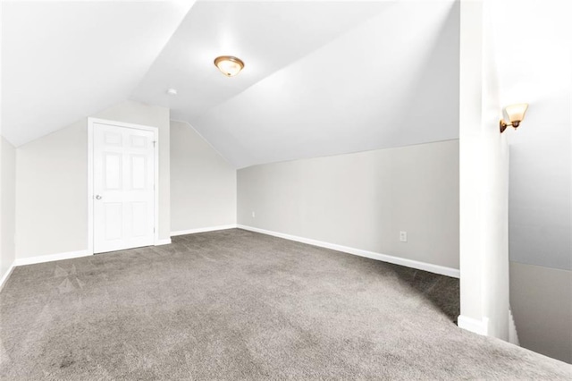 additional living space featuring lofted ceiling and dark carpet