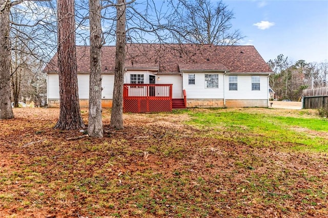 rear view of house featuring a wooden deck and a yard