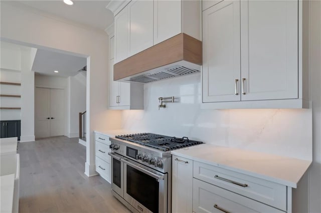 kitchen with white cabinets, decorative backsplash, range with two ovens, light hardwood / wood-style floors, and custom range hood