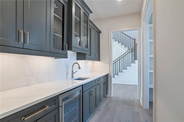 interior space with tasteful backsplash, sink, beverage cooler, and light wood-type flooring