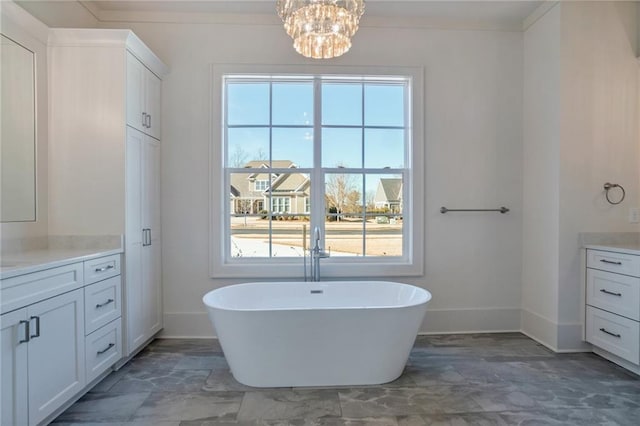 bathroom with an inviting chandelier, vanity, a bathtub, and a wealth of natural light