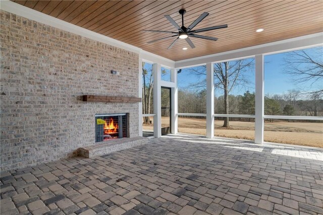 unfurnished sunroom featuring an outdoor brick fireplace, wood ceiling, and ceiling fan