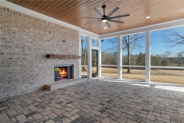 unfurnished sunroom featuring an outdoor brick fireplace, ceiling fan, and wooden ceiling