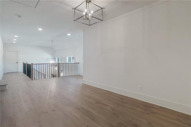 empty room featuring an inviting chandelier and wood-type flooring