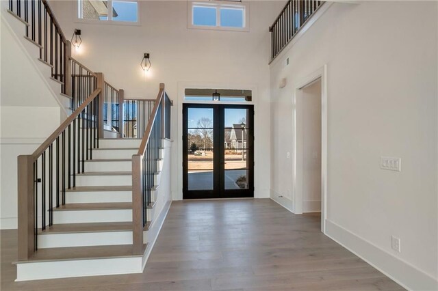 foyer entrance featuring french doors, hardwood / wood-style floors, and a high ceiling