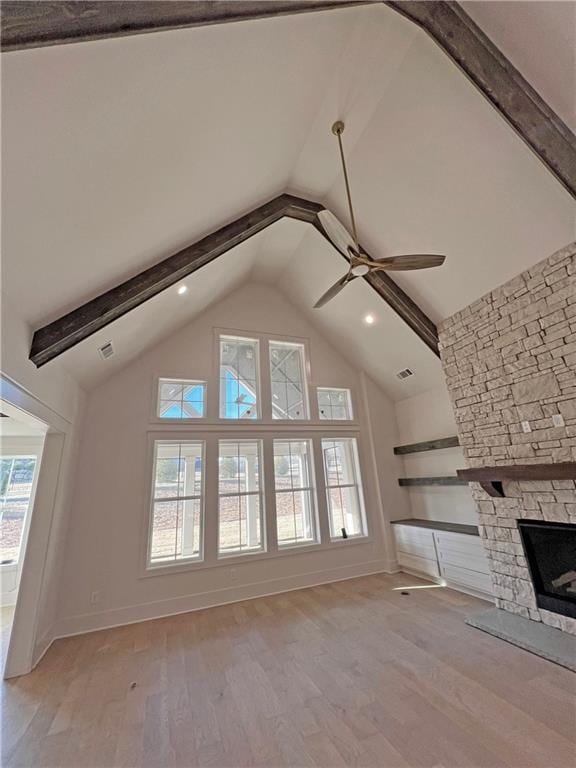 unfurnished living room with ceiling fan, light wood-type flooring, a healthy amount of sunlight, and a stone fireplace