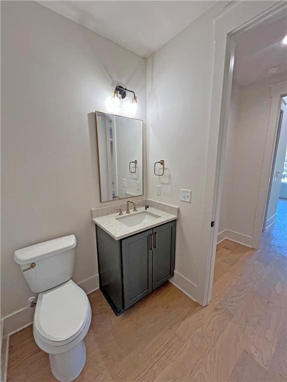 bathroom featuring toilet, wood-type flooring, and vanity