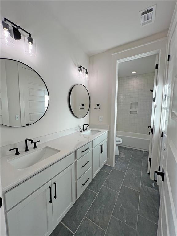 full bathroom featuring toilet, vanity, tile patterned flooring, and tiled shower / bath combo