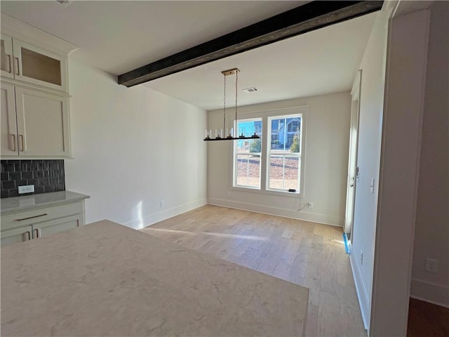 unfurnished dining area featuring beam ceiling, light hardwood / wood-style floors, and a notable chandelier