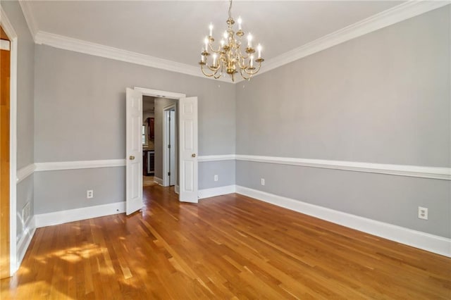 unfurnished room featuring wood-type flooring, crown molding, and a chandelier