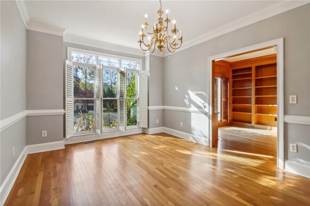 unfurnished room featuring hardwood / wood-style flooring, an inviting chandelier, and ornamental molding