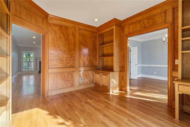 unfurnished living room featuring ornamental molding, a notable chandelier, and light wood-type flooring